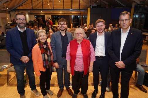 Gruppenfoto der Teilnehmer der Pdoiumsdisskussionen, sie stehen nebeneinander im Veranstaltungssaal und blicken in die Kamera.