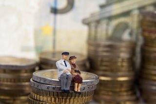 Symbolbild, zwei Figuren für Rentnerin und Rentner sitzen auf einer Euromünze, im Hintergrund Euroscheine