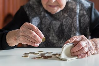 ltere Frau am Tisch beim Geld zählen mit ihrer Brieftasche