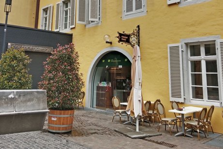 Au&szlig;enansicht auf das Caf&eacute; Schwarzes Kloster, der Himmel ist bew&ouml;lkt, das Geb&auml;ude ist in einem freundlichen gelb gestrichen, vor dem Haupteingang steht ein Pflanzenk&uuml;bel.