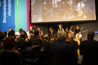 Die Gäste im Saal applaudieren, die Streicherinnen auf der Bühne verbeugen sich.