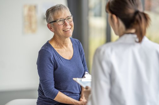 Senior bei einem Gesundheits-Check-Up beim facharzt, sie spricht mit der &Auml;rztin, diese h&auml;lt ein Klemmbret und tr&auml;gt einen wei&szlig;en Kittel.