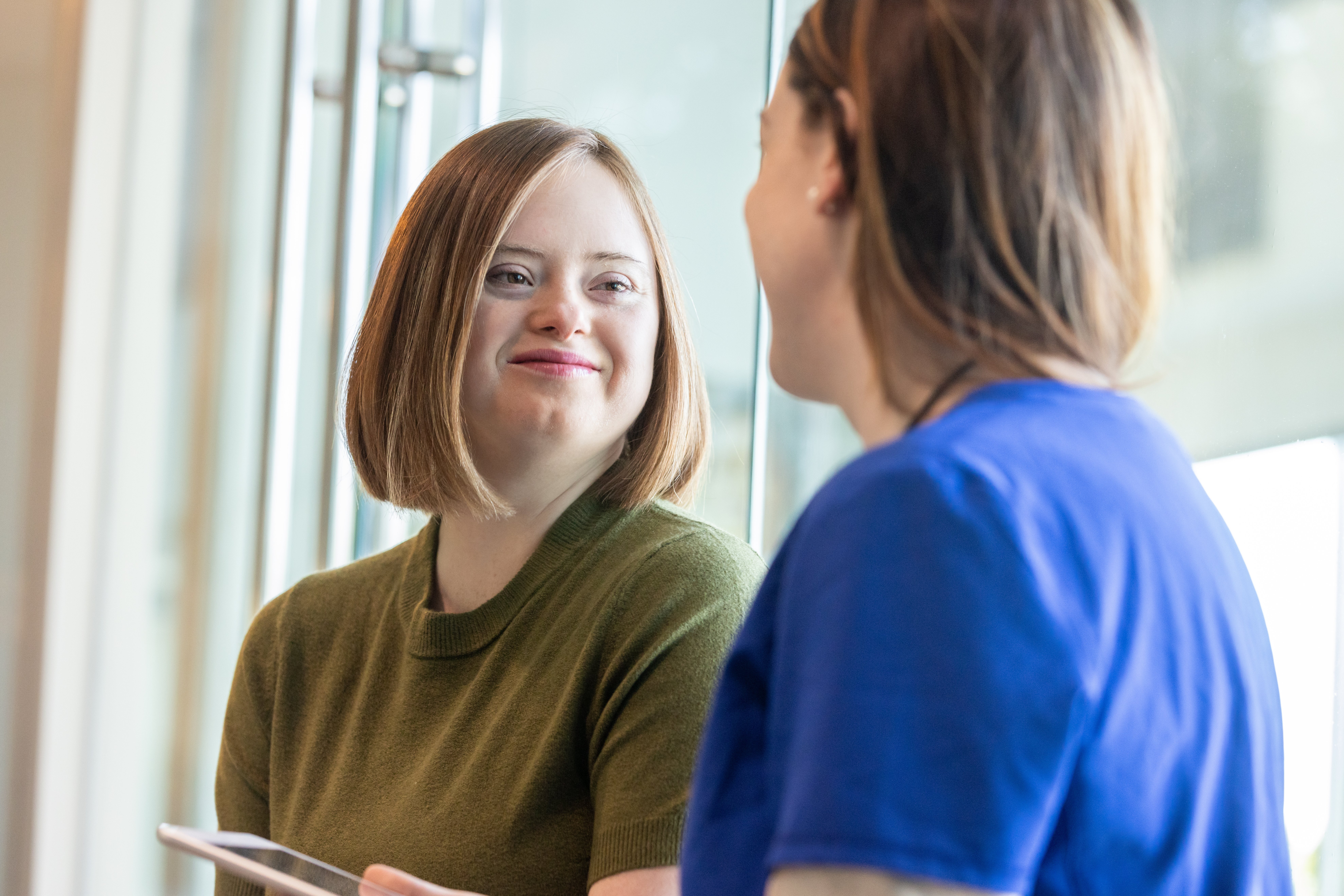 Junge erwachsene Frau mit Down-Syndrom im Gespr&auml;ch mit ihrer &Auml;rztin.