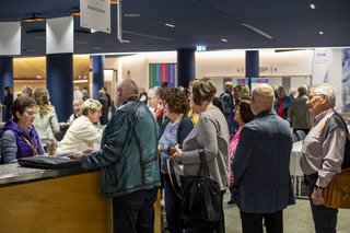 Menschen stehen Schlange am Schalter, um ihre Unterlagen abzuholen.