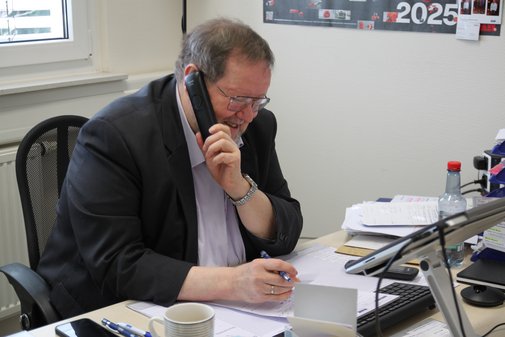VdK-Sprechstunde in Ubstadt mit Reinhold Gsell Reinhold Gsell sitzt an seinem Schreibtisch, einen Stift in der rechten Hand und den Telefonhörer in der linken am Ohr.