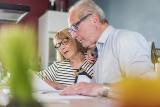 Zwei ältere Personen sitzen an einem Computer und blicken auf den Bildschirm