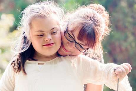 Mutter umarmt ihr Kinder mit Down-Syndrom