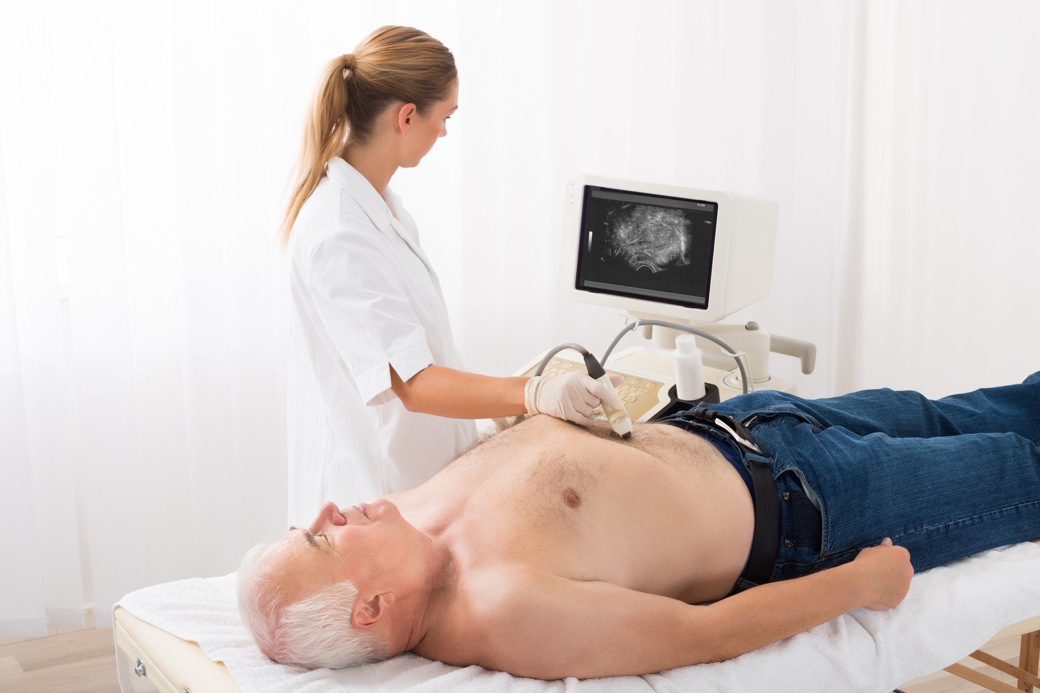 Ärztin mit Ultraschall am Bauch einesmännlichen Patienten