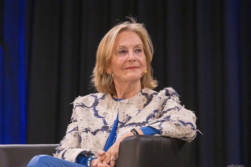 ortr&auml;t von Gaby Hauptmann auf der B&uuml;hne. Sie tr&auml;gt eine gemusterte, hellblaue Jacke, sitzt mit verschr&auml;nkten H&auml;nden im Sessel und blickt l&auml;chelnd zur Seite.