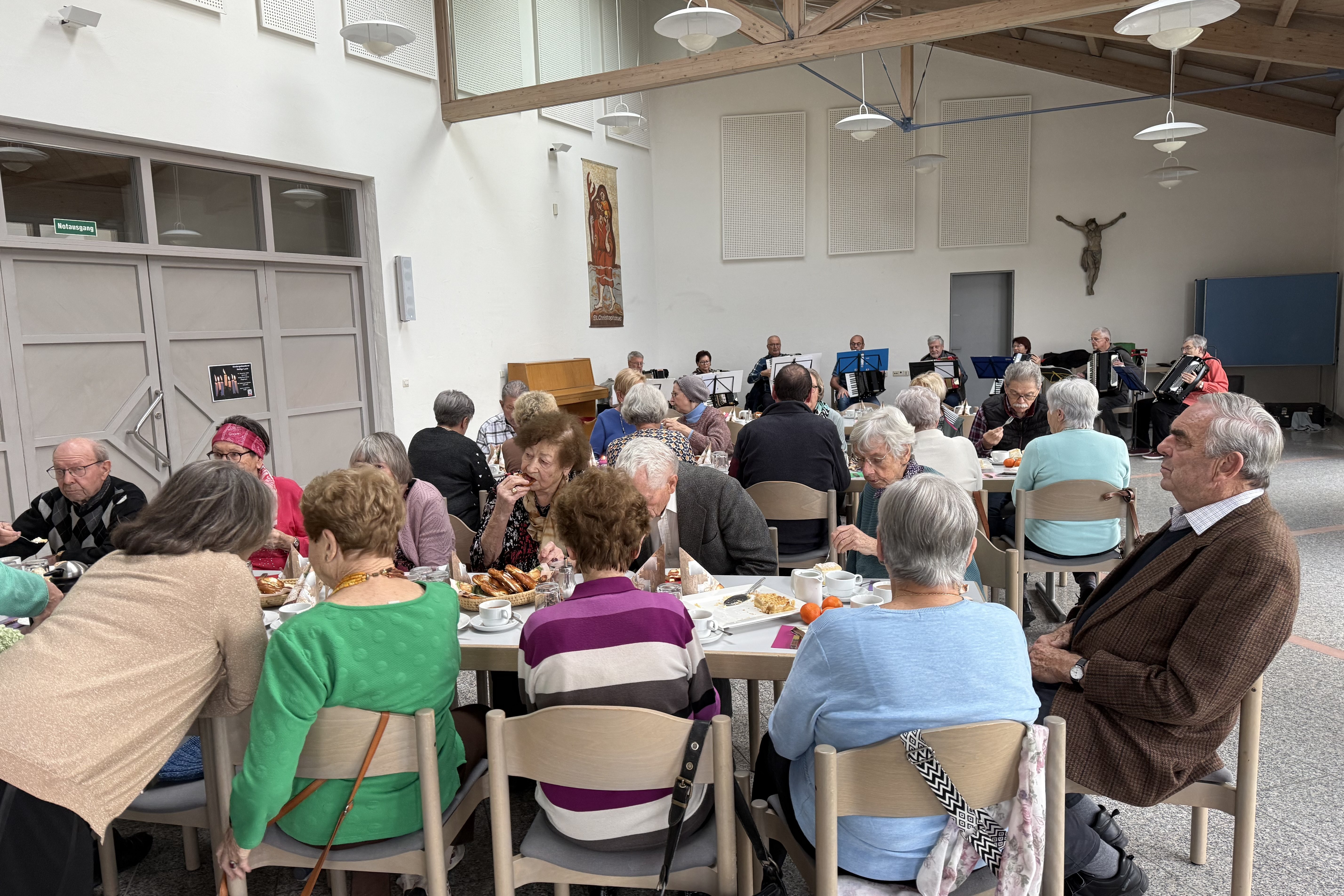 Menschen sitzen an Tischen und essen. Im Hintergrund spielt eine Band.
