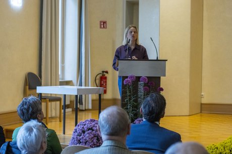 Bentele am Rednerpult auf der Bühne, sie spricht ins Mikrofon, im Vordergrund sind die Köpfe der Zuschauer zu sehen