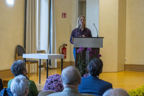 Bentele am Rednerpult auf der Bühne, sie spricht ins Mikrofon, im Vordergrund sind die Köpfe der Zuschauer zu sehen