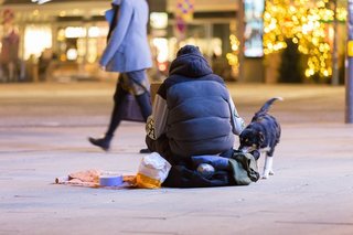 Obdachloser Mann sitzt auf der Straße und bettelt um Geld.