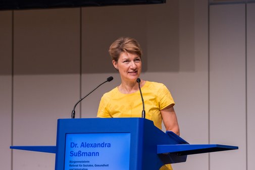 Dr. Alexandra Sußmann VdK-Gesundheitstag Dr. Alexandra Sußmann spricht ins Mikrofon am Rednerpult auf der Bühne