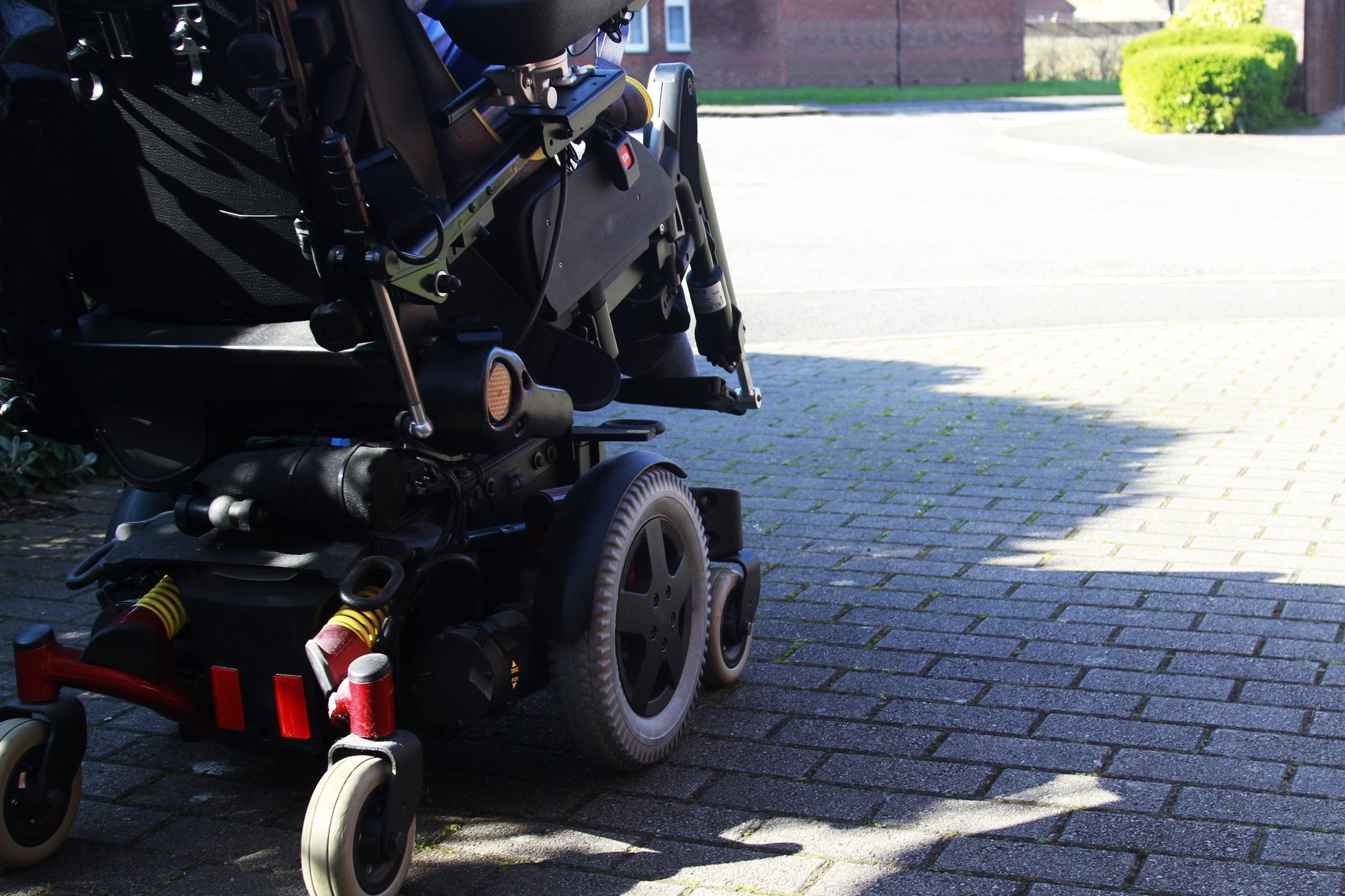 Seitenansicht eines Elektrorollstuhls, der auf einer Stra&szlig;e f&auml;hrt.