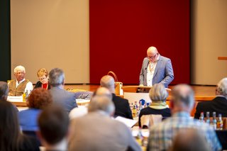 Blick aus der Menge aufs Podium, am Mikrofon steht Stefan Pfeil und spricht.