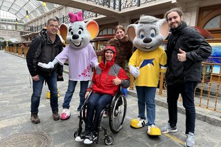 Das Team Barrierefreiheit von Freizeitpark Erlebnis posiert mit der Euro-Maus im Europa-Park, mittendrin ein Rollstuhlfahrer mit dem der Europa-Park live auf Barrierefreiheit getestet wird.