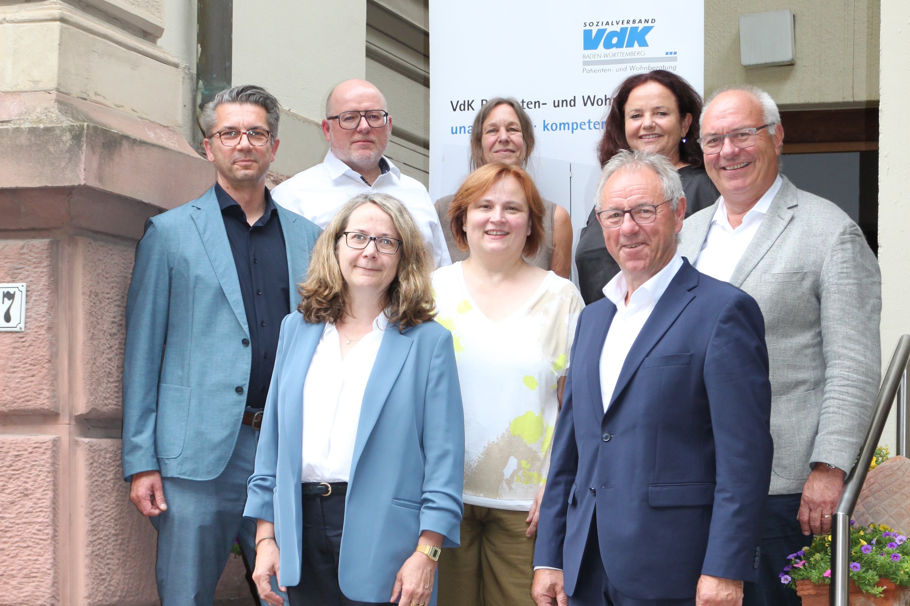 Gruppenfoto von Mitglieder des Sozialverbands VdK, der VdK-Patientenberatung und der Stiftung Unabhängige Patientenberatung Deutschland verteilt auf zwei Treppenstufen am Eingang der UPD.