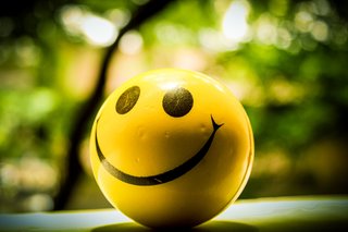 Gelber Schaumstoffball mit einem lächelnden Smiley-Gesicht aufgemalt