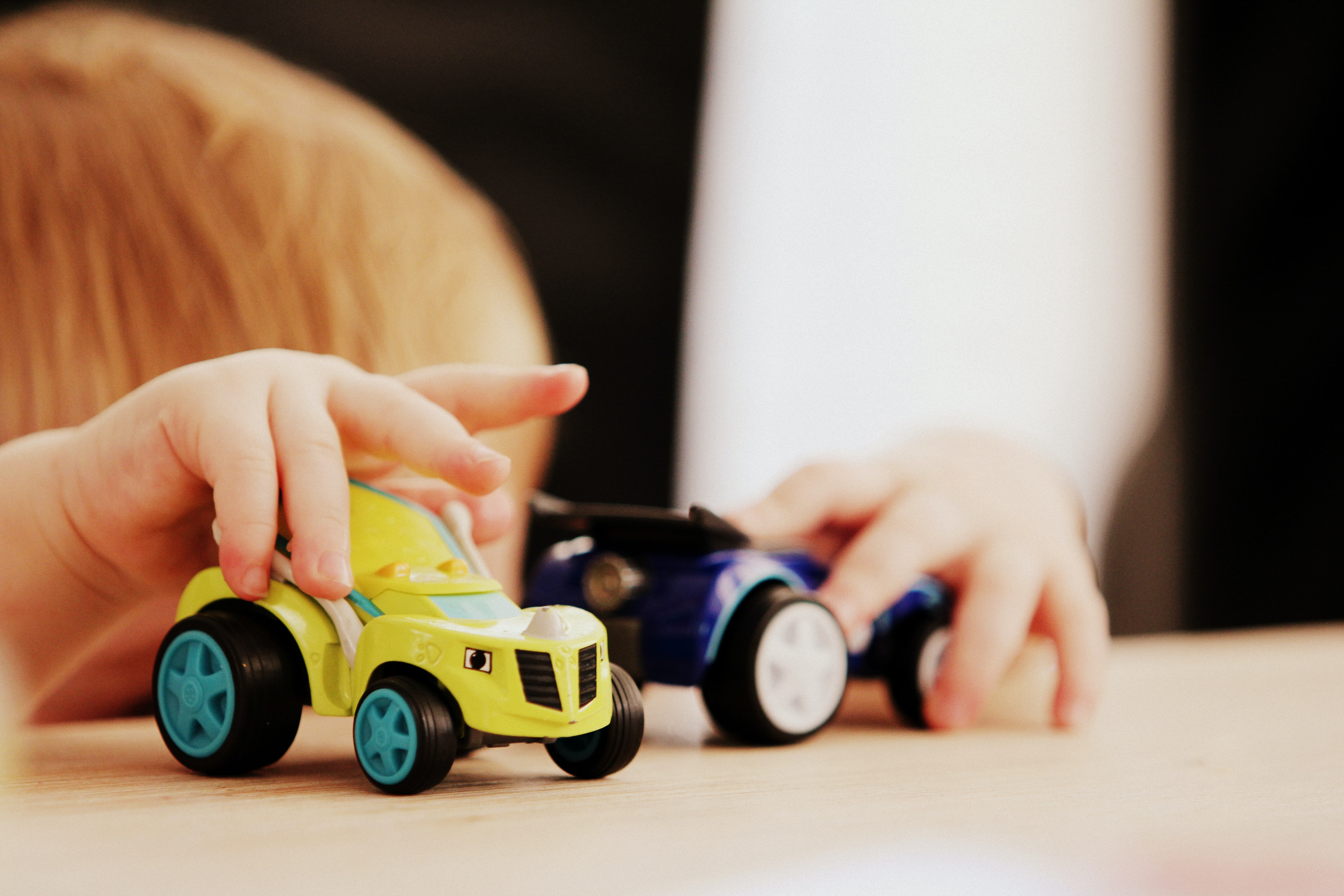 Kind spielt an einem Tisch mit zwei Spielzeugautos