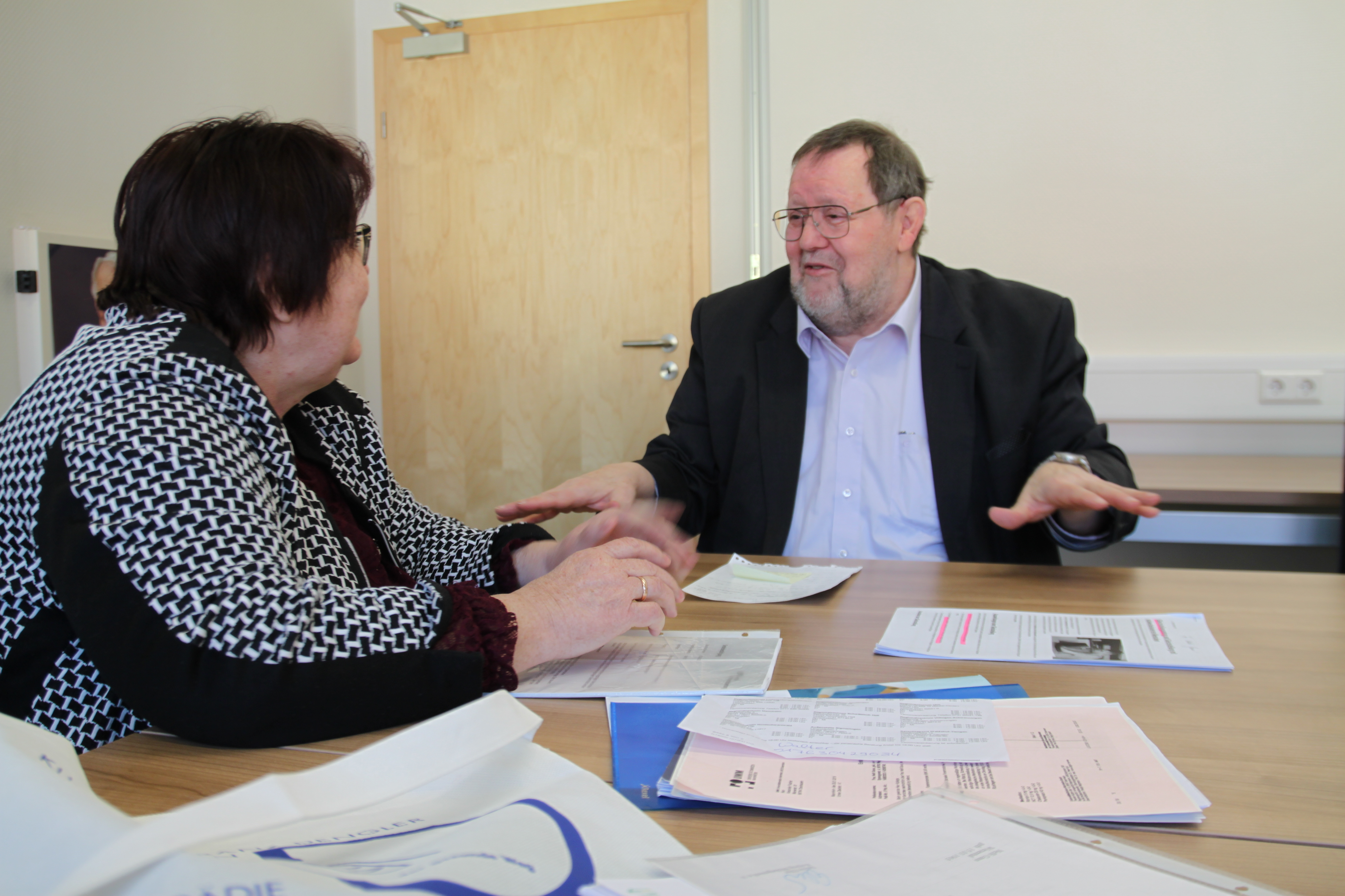 Beratungsgespräch bei VdK: Herr Gsell sitzt mit einer Frau am Tisch, sie sind ins Gespräch vertieft.
