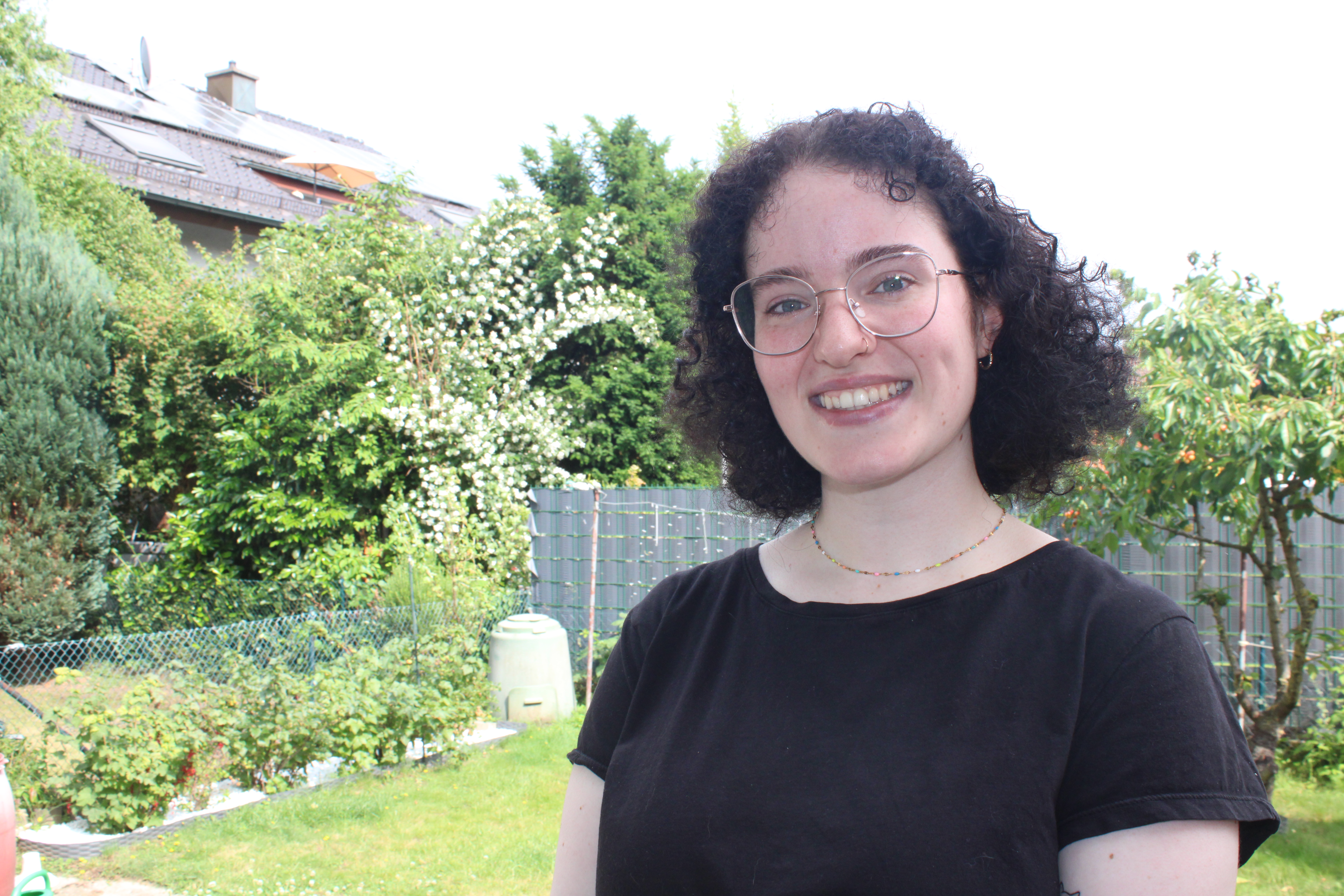 Portraitaufnahme von Nicole Zierat, im Hintergrund ist ein garten zu sehen, sie lacht in die Kamera