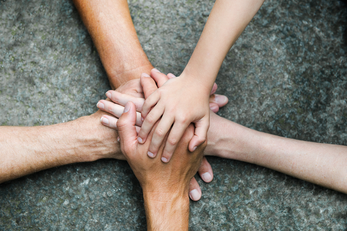 Hände zusammen für Gemeinschaft Fünf Personen legen jeweils eine Hand aufeinander, so dass ein Kreis bzw. ein Stern entsteht