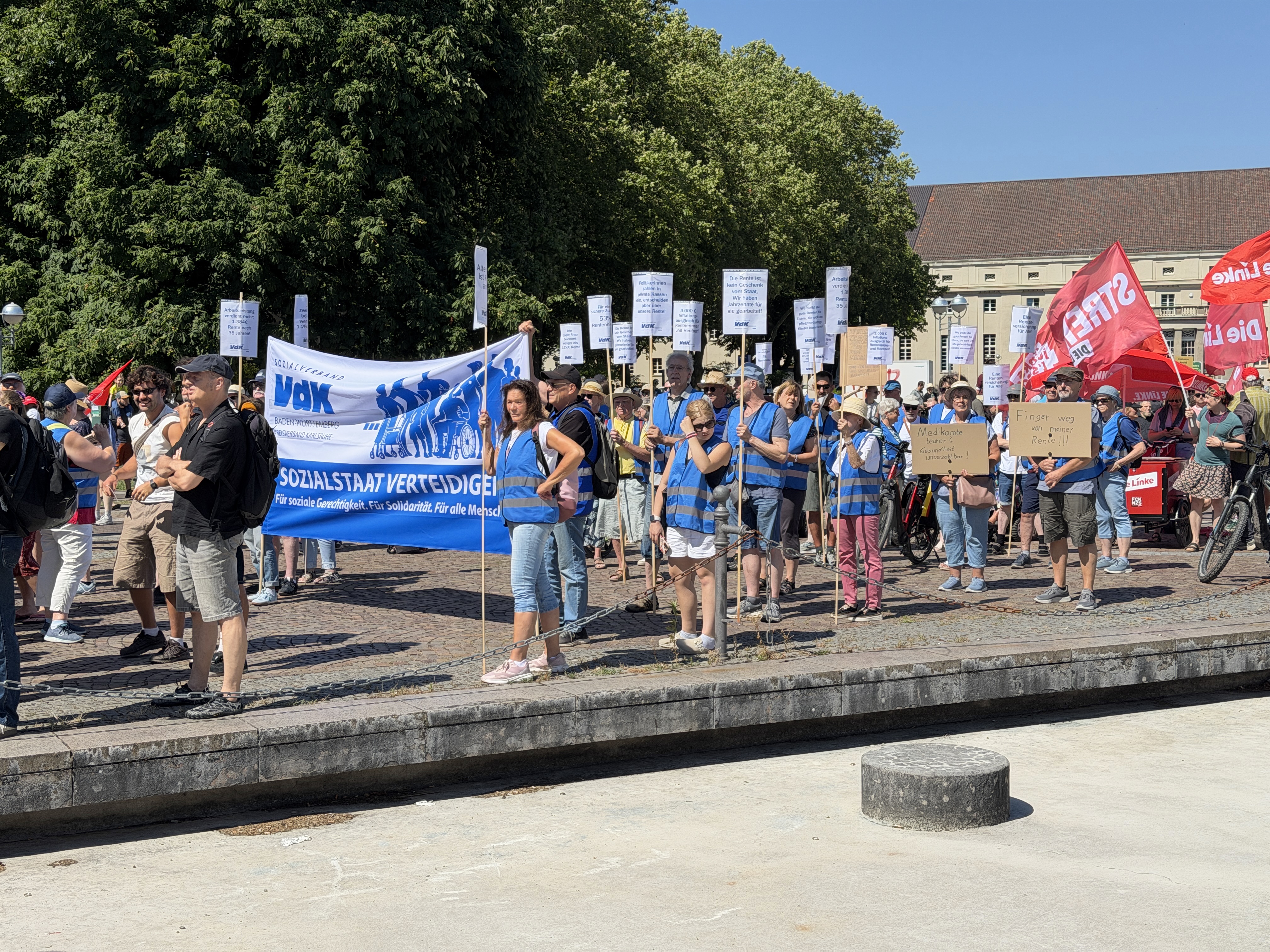 Demonstrationszug: Menschen mit Banner und Plakaten laufen durch die Innenstadt von Karlsruhe, die Sonne scheint.