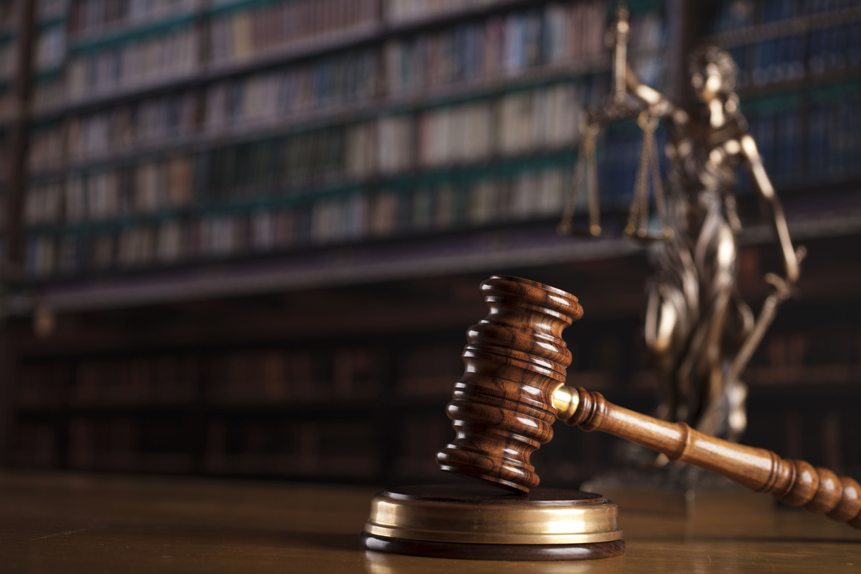 Sozialverband VdK Sozialrecht Beratung Nahaufnahme eines Richterhammers, dahinter ist eine Figur von Justizia zu sehen, hinter ihr ein Bücherregal.