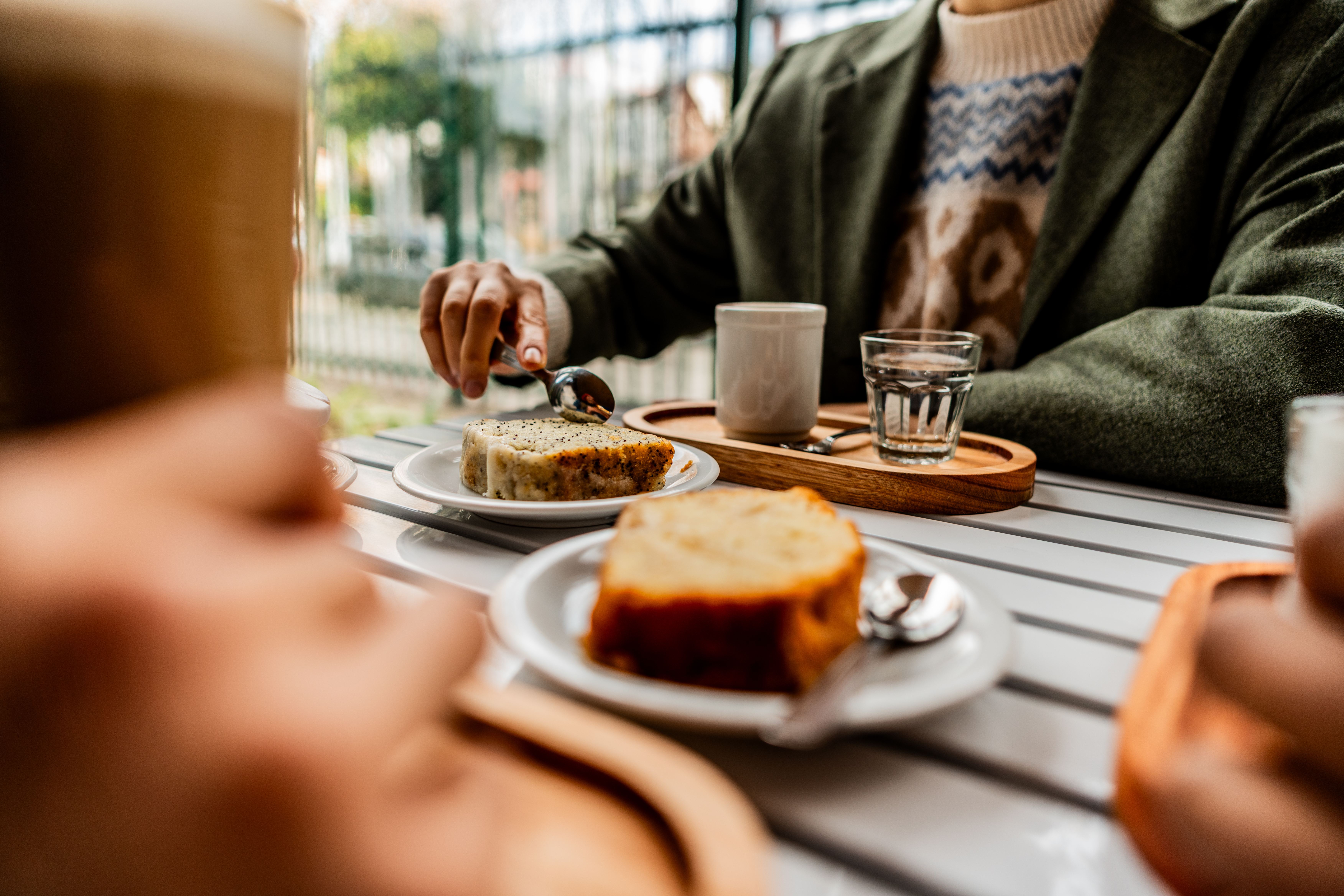 Nahaufnahme einer Frau, die mit Freunden Kuchen isst und Kaffee trinkt.