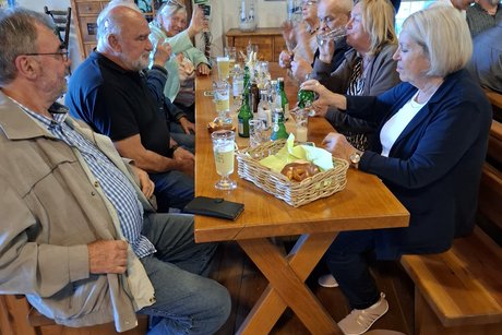 Die Teilnehmenden des VdK OV St. Georgen sitzen am Tisch und nehmen an der Bierverkostung teil und essen die dazu gereichten Brezeln.