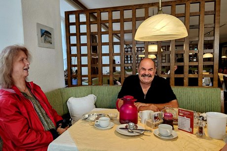 Zwei Mitglieder eine lachende Frau und ein Mann am Wirtshaustisch.
