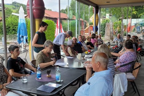 mehrere Personen an Tischen beim Sommertreff im Minigolf