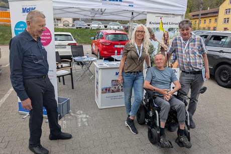 Erhard Sch&ouml;pflin vom Kreisverband, Angela Gutmann und R&uuml;diger Hasberg, stehend am Infostand des VdK mit Besucher J&uuml;rgen Wechlin mit Elektrorollstuhl