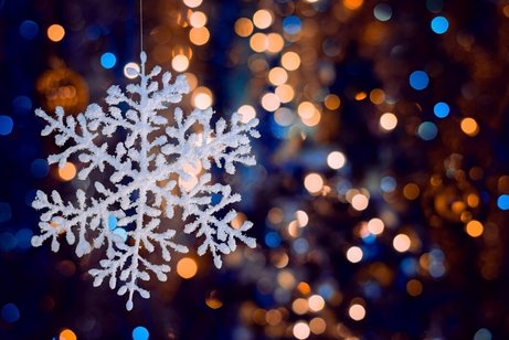 Schneeflocke mit Lichterschein im Hintergrund