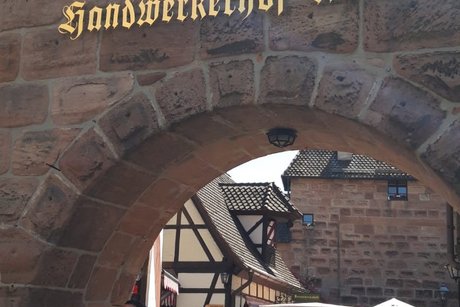 Bild zeigt Personen vor dem Rundbogen zum Krämermarkt