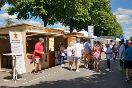 Viele Menschen laufen entlang einer Straße, an der sich auf der linken Seite zahlreiche Informationsstände aneinanderreihen.
