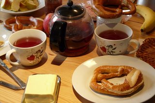 Frühstückstisch mit Tee und Brezeln und Butter