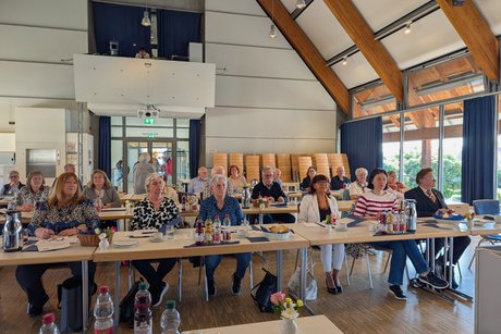 Blick von vorne auf die rechte Seite der vordersten Tischreihe, in der die Vertreter der Ortsverb&auml;nde dem Vortrag aufmerksam folgen.