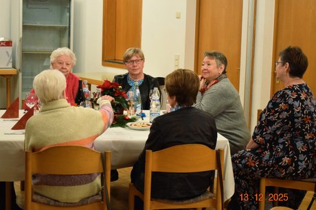 Sechs Frauen sitzen gemeinsam an einem Tisch und unterhalten sich.