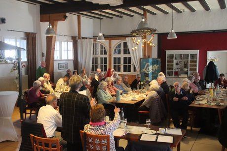 Mitglieder sitzen an Tischen beim Kaffee trinken und Kuchen essen