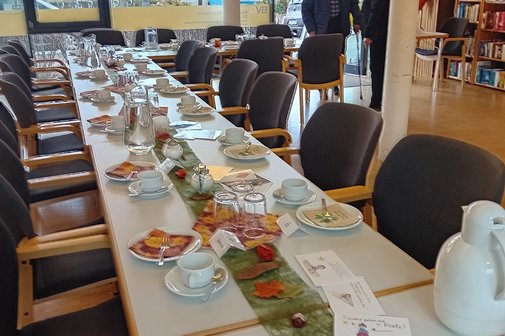 Tafel mit Kaffeegeschirr und Deko wartet auf Besuchende