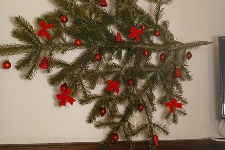 Tannenzweig mit roten Kugeln an der Wand