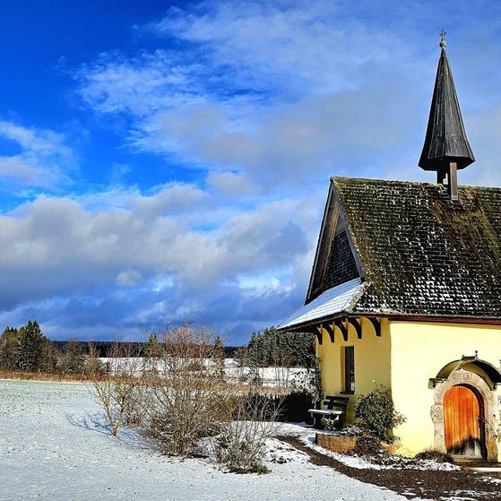 Kapelle im Schnee, blauer Himmel und ein paar Wolken.