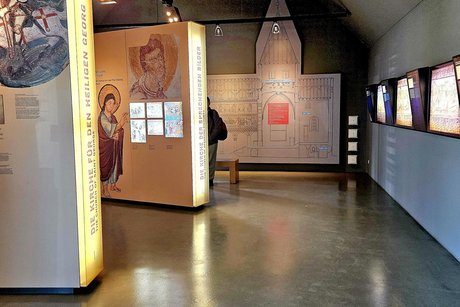 Ein Blick in das Museum der Kirche, alles dunkel gehalten mit beleuchteten Schautafeln sehr modern.n