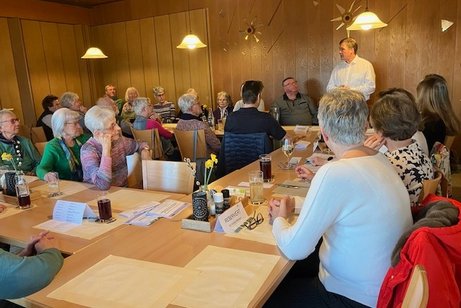 Teilnehmerrunde an mehreren Tischen mit Referent