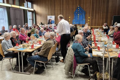 man sieht Mitglieder an festlich gedeckten Tischen sitzen