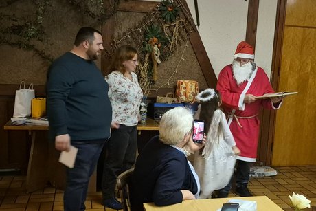 W&auml;hrend der Nikolaus aus dem goldenen Buch liest, hilft sein kleines Engelchen beim Wichteln