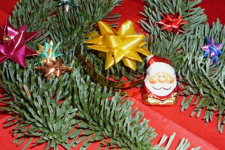 Zwischen Tannenzweigen ein kleiner Schokoladen-Nikolaus. Darum herum gebastelte Weihnachtssterne.