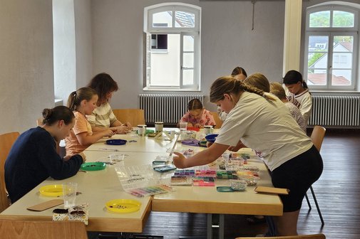 mehrere Personen um einen Tisch gruppiert, konzentriert bei der Arbeit